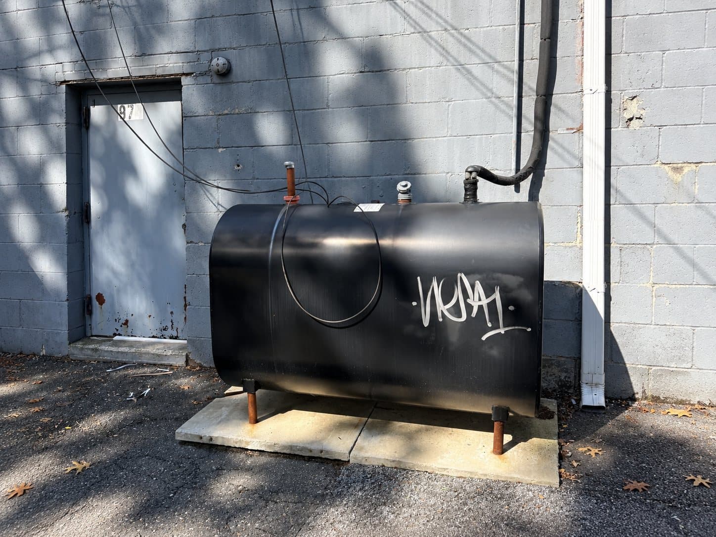 Aboveground tank beside a masonry building.